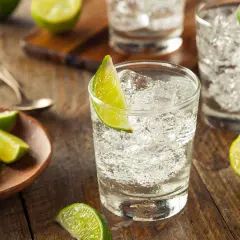 Erfrischende Cocktails mit Gin und Limette, serviert auf rustikalem Holz.