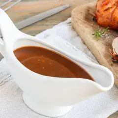 Sternekoch-Qualität: Eine weiße Sauciere mit glänzender Portweinsauce neben einem saftigen Braten.