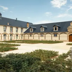 Der Innenhof von Maison Ruinart mit moderner Skulptur und grünen Büschen.