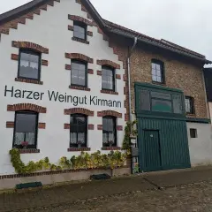 Das Harzer Weingut Kirmann präsentiert sich mit weißer Fassade und roten Ziegelakzenten. Ranken schmücken die Hauswand.