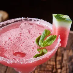 Erfrischender weihnachtscocktail mit sekt, garniert mit Wassermelone und Minze, auf rustikalem Holz.