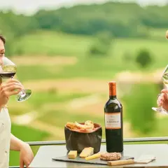 Ein Paar genießt Wein und Käse auf der Terrasse eines Weinguts in Bordeaux. Die Weinprobe verspricht Genuss.