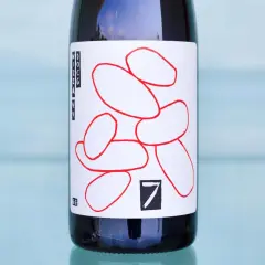 Flasche mit Etikett, das rote, abstrakte Formen und die Aufschrift "Nizza Monferrato" zeigt.