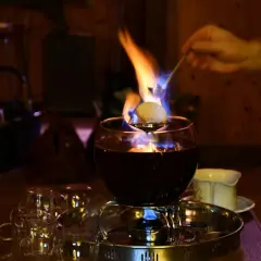 Eine alkoholfreie Feuerzangenbowle brennt und verströmt wohlige Wärme. Ein Zuckerhut schmilzt über der Flamme.