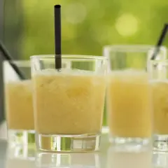 Erfrischende Cocktails, perfekt für ein Coco Vine Rezept. Sonnengelbe Drinks mit Eis und schwarzen Strohhalmen.