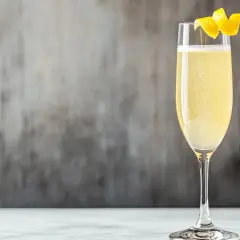 Ein spritziger French 75 Cocktail, dessen Geschichte bis ins frühe 20. Jahrhundert zurückreicht, garniert mit einer Zitronenzeste.