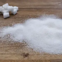 Zuckerwürfel und ein Haufen feiner Zuckerkristalle auf Holz. Ein visueller Hinweis auf den trauben zuckergehalt in Lebensmitteln.