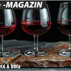 Drei Gläser Rotwein stehen auf Steinplatten. Die d.o.c. Bedeutung von Wein wird hier thematisiert.