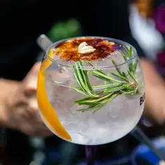 Ein erfrischender Gin Tonic mit Rosmarin und karamellisierter Orangenscheibe, einer der besten Gin Cocktails.