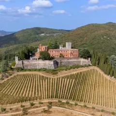 Ein Schloss thront auf einem Hügel inmitten von Weinbergen und Olivenhainen in der Chianti-Region der Toskana.