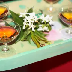 Bernsteinfarbene Likörgläser auf einem Tablett mit Blumen. Eine elegante Alternative zu Vin Santo für besondere Anlässe.