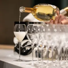 Ein Glas wird mit prickelndem Vranken Pommery gefüllt, daneben stehen weitere Champagnergläser bereit.