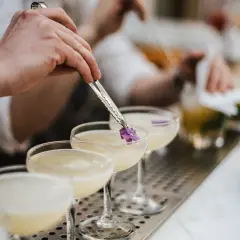 Ein Barkeeper garniert einen Cocktail mit Cointreau und Sekt mit einer kleinen Blüte.