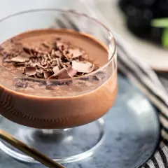 Cremiges Schokoladen-Dessert, wie eine zabaione ohne alkohol, garniert mit Schokostückchen. Daneben Beeren und ein goldenes Löffelchen.