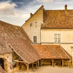 Historisches Gebäude mit Ziegeldächern, ein Torbogen und ein Sonnenuhr. Vielleicht ein Ort, wo man einen exzellenten Chambertin Clos de Bèze genießt.