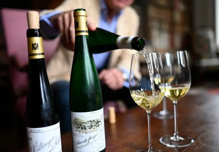 Egon Müller schenkt Wein aus zwei Mosel-Flaschen in Weingläser.
