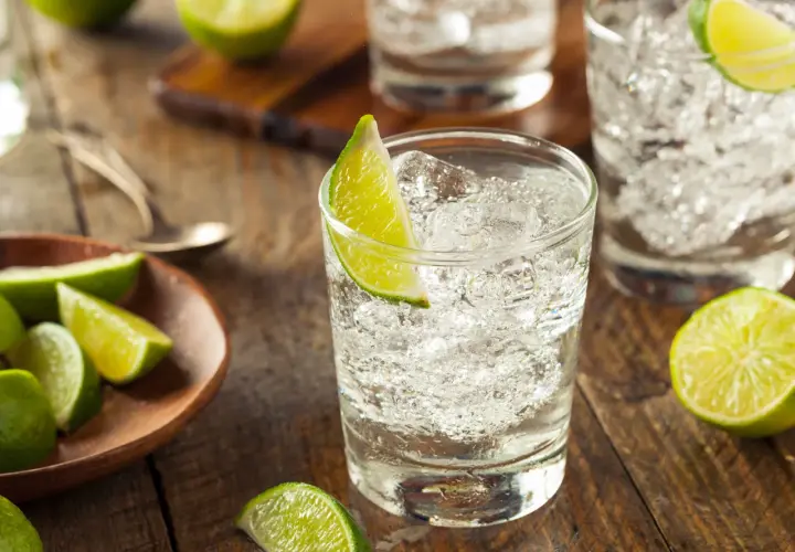 Erfrischende Cocktails mit Gin und Limette, serviert auf rustikalem Holz.