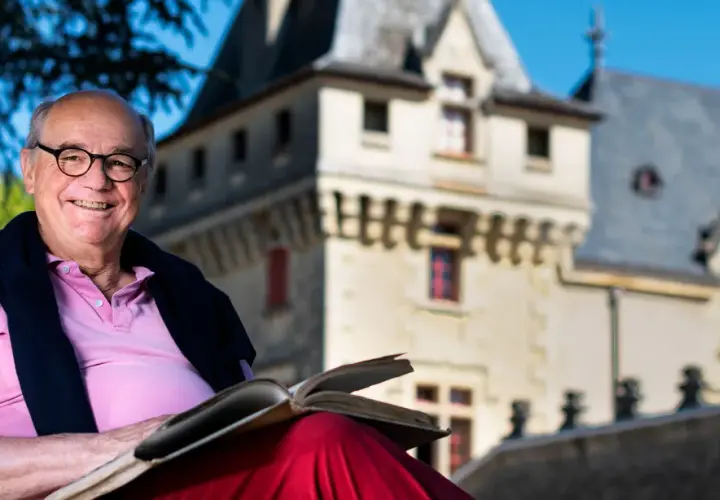 Ein Mann mit Brille liest ein Buch vor dem **Château de Pressac**.