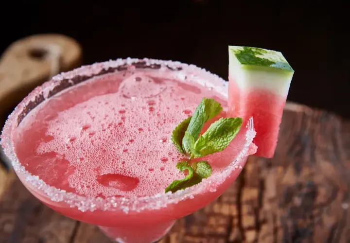 Erfrischender weihnachtscocktail mit sekt, garniert mit Wassermelone und Minze, auf rustikalem Holz.