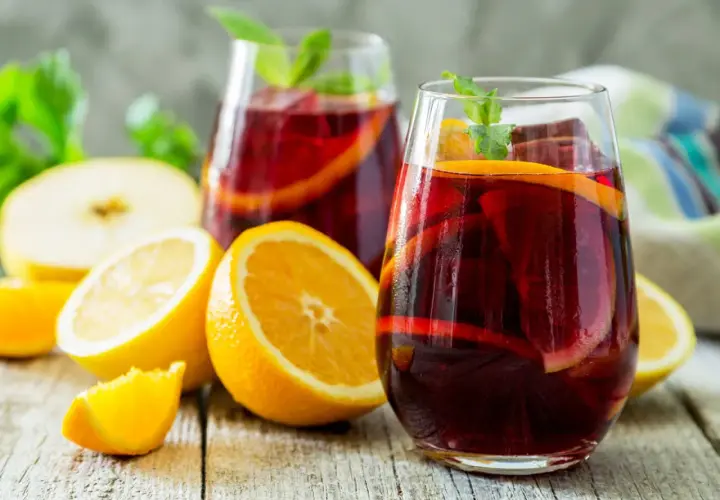 Erfrischender Sangria mit Orangen- und Zitronenscheiben, Minze und Eis. Das beste Sangria Rezept für heiße Tage.