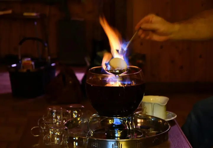 Eine alkoholfreie Feuerzangenbowle brennt und verströmt wohlige Wärme. Ein Zuckerhut schmilzt über der Flamme.