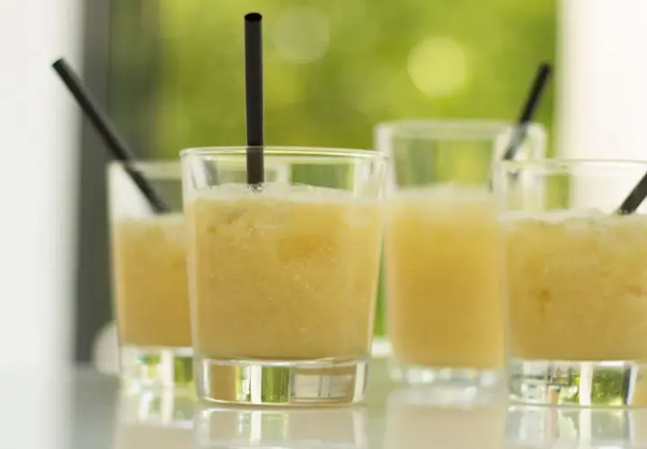 Erfrischende Cocktails, perfekt für ein Coco Vine Rezept. Sonnengelbe Drinks mit Eis und schwarzen Strohhalmen.
