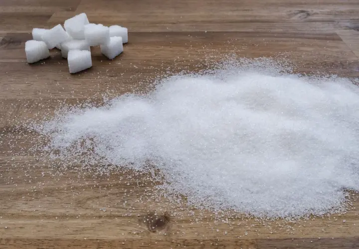 Zuckerwürfel und ein Haufen feiner Zuckerkristalle auf Holz. Ein visueller Hinweis auf den trauben zuckergehalt in Lebensmitteln.
