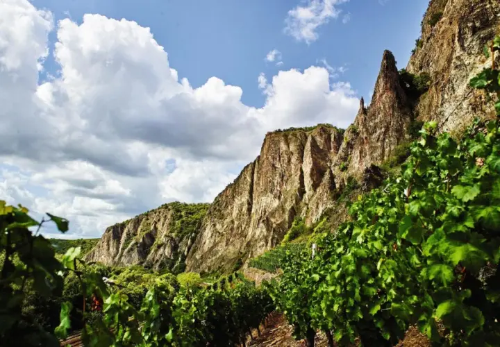 Steile Weinberge am Felsen, die auf die besten Naheweine hoffen lassen. Wolken ziehen über die beeindruckende Landschaft.