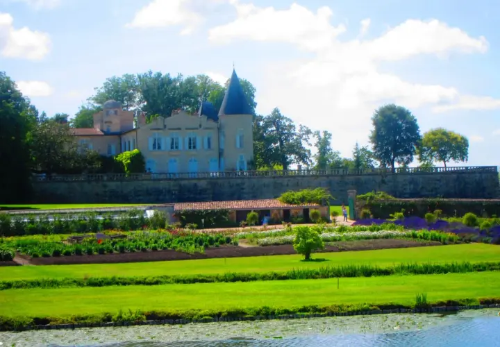 Schloss mit Türmchen und Gartenanlage, davor ein Teich.