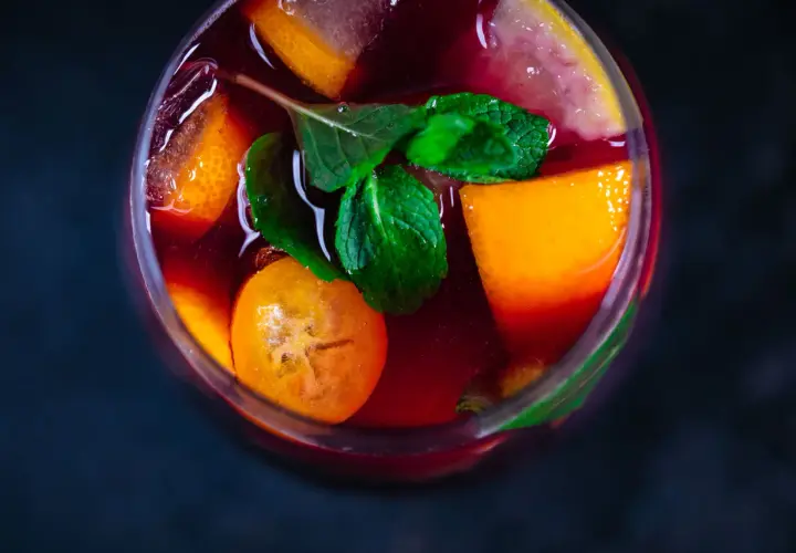 Erfrischender Sangria mit Orangen-, Zitronen- und Kumquat-Scheiben sowie Minze. Die Zutaten Sangria sind perfekt für einen heißen Sommertag.