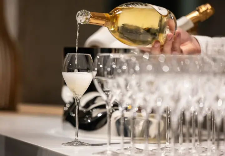 Ein Glas wird mit prickelndem Vranken Pommery gefüllt, daneben stehen weitere Champagnergläser bereit.