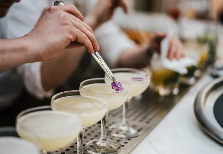 Ein Barkeeper garniert einen Cocktail mit Cointreau und Sekt mit einer kleinen Blüte.
