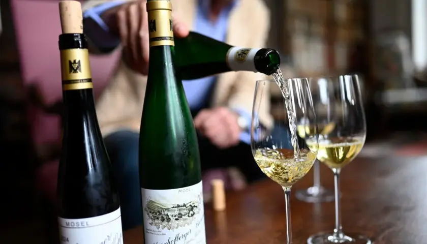 Egon Müller schenkt Wein aus zwei Mosel-Flaschen in Weingläser.