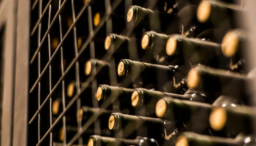 Reihe von dunklen Flaschen mit Korken, die in einem Regal gelagert werden. Vielleicht der teuerste Wein der Welt, der auf seine Reifung wartet.