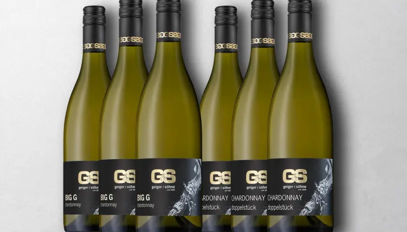 Sechs Flaschen Chardonnay von "BIG G" im Vergleich zu Pinot Grigio. Elegante goldene Etiketten auf schwarzem Grund.