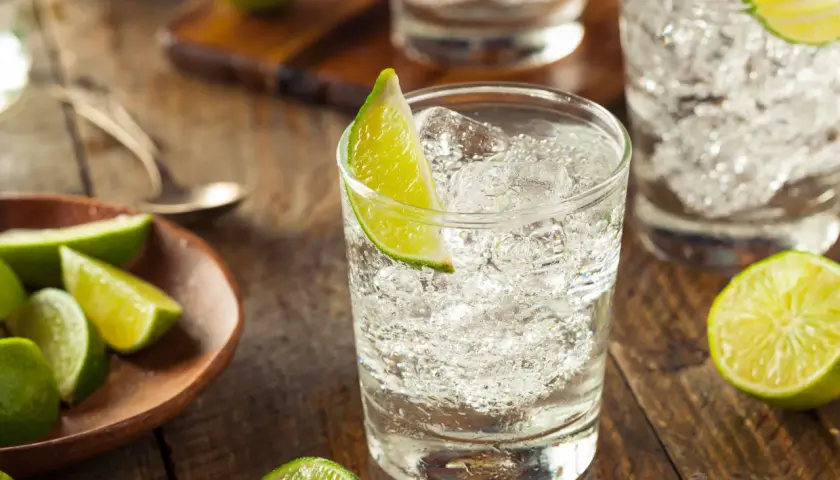 Erfrischende Cocktails mit Gin und Limette, serviert auf rustikalem Holz.