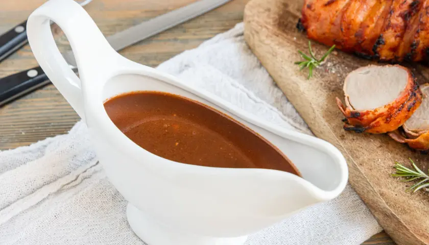 Sternekoch-Qualität: Eine weiße Sauciere mit glänzender Portweinsauce neben einem saftigen Braten.