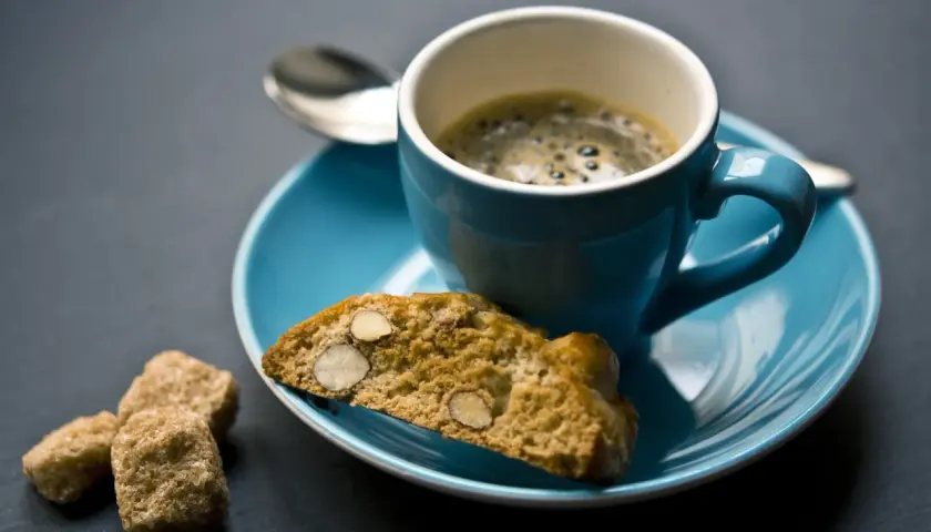 Ein Espresso mit Cantuccini und braunem Zucker, perfekt zum Genießen eines italienischen Dessertweins.