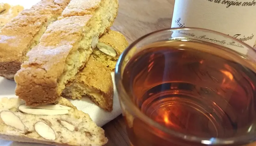 Cantuccini mit Mandeln und ein Glas süßer Dessertwein aus der Toskana, perfekt für einen Genussmoment.