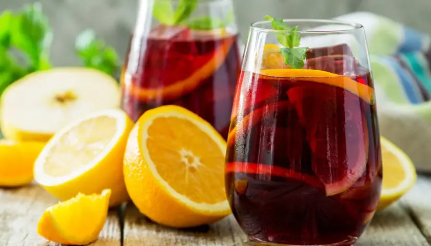 Erfrischender Sangria mit Orangen- und Zitronenscheiben, Minze und Eis. Das beste Sangria Rezept für heiße Tage.