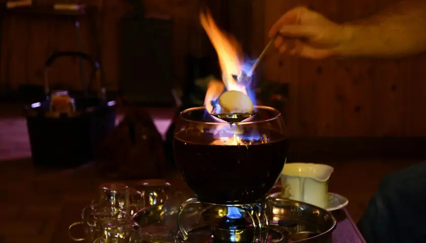 Eine alkoholfreie Feuerzangenbowle brennt und verströmt wohlige Wärme. Ein Zuckerhut schmilzt über der Flamme.