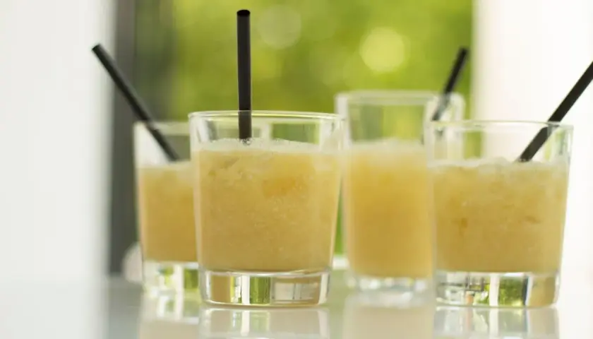 Erfrischende Cocktails, perfekt für ein Coco Vine Rezept. Sonnengelbe Drinks mit Eis und schwarzen Strohhalmen.