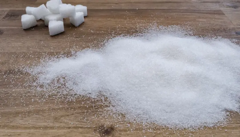 Zuckerwürfel und ein Haufen feiner Zuckerkristalle auf Holz. Ein visueller Hinweis auf den trauben zuckergehalt in Lebensmitteln.