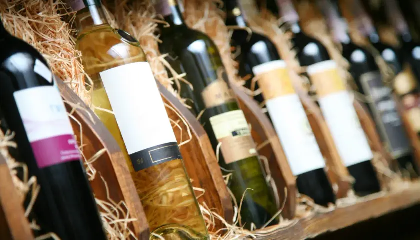 Reihe von Flaschen mit Wein, einige rot, andere weiß, in Holzkisten mit Stroh. Ein Genuss für jeden Weinliebhaber.
