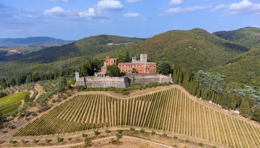 Ein Schloss thront auf einem Hügel inmitten von Weinbergen und Olivenhainen in der Chianti-Region der Toskana.