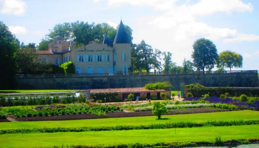 Schloss mit Türmchen und Gartenanlage, davor ein Teich.