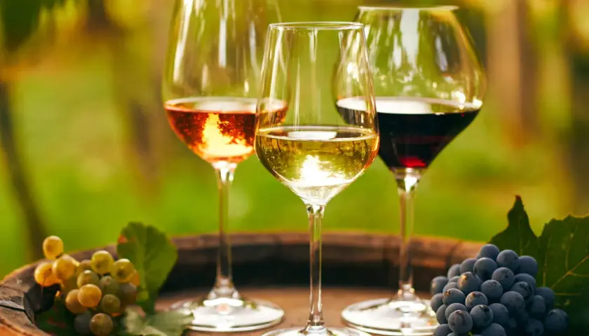 Drei Gläser Wein – Rosé, Weiß und Rot – stehen auf einem Holzfass. Daneben Trauben, die an einen Besuch im **Château Lafleur** erinnern.
