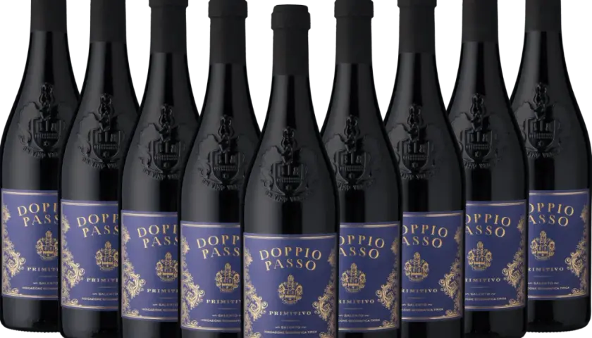 Reihe von Flaschen "Doppio Passo Primitivo" Wein mit dunkelblauen Etiketten und goldener Schrift, vor dunklem Hintergrund.