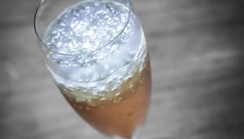 Ein prickelnder Champagner-Cocktail mit feinem Schaum und Bläschen in einem eleganten Glas.