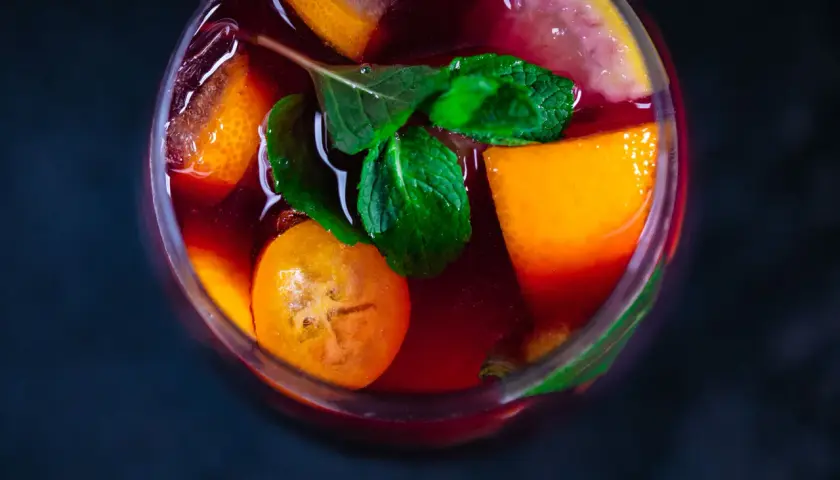 Erfrischender Sangria mit Orangen-, Zitronen- und Kumquat-Scheiben sowie Minze. Die Zutaten Sangria sind perfekt für einen heißen Sommertag.